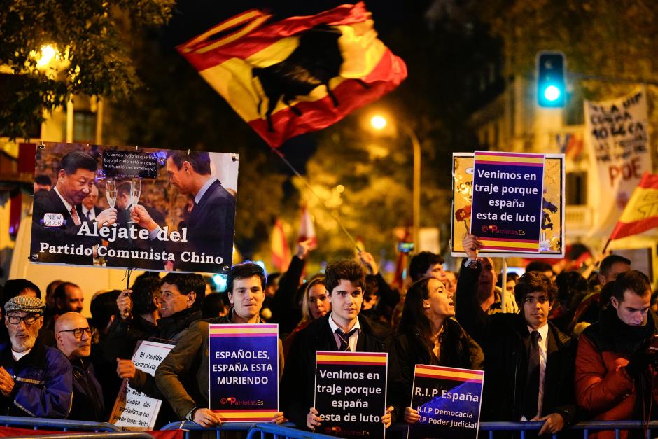 Unos jóvenes vestidos de traje en la manifestación frente a la sede del PSOE