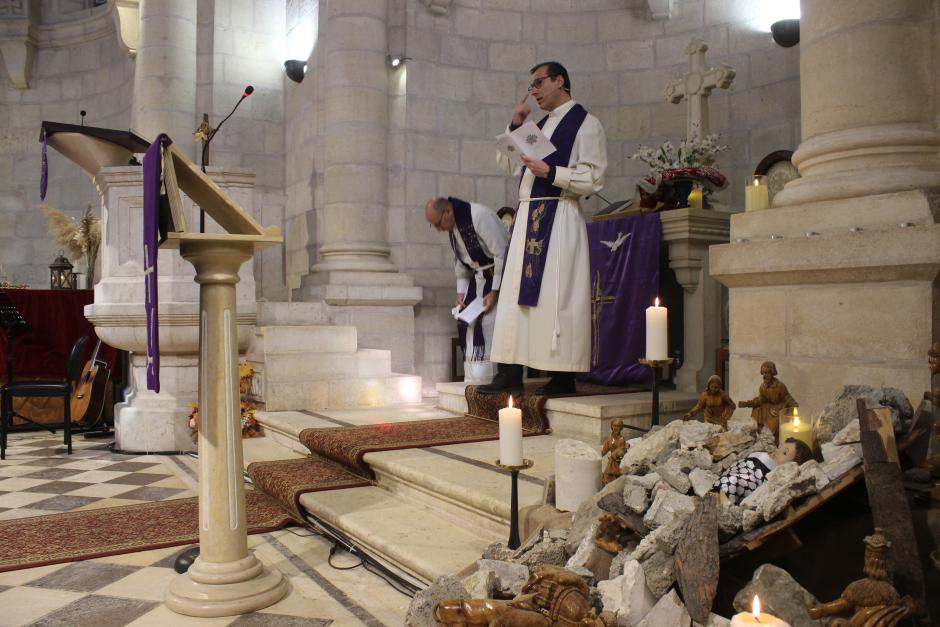 El reverendo Munther Isaac durante una misa junto al nacimiento con un Niño Jesús entre ruinas en Belén