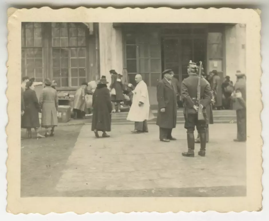 Mientras los residentes judíos se reúnen en Breslau, un policía alemán con un rifle oculta parcialmente al jefe de operaciones de la Gestapo.