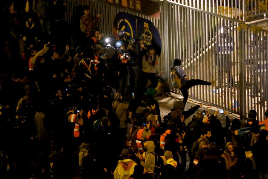 Un manifestante dando una patada a las puertas del Camp Nou, custodiado por un cordón policial