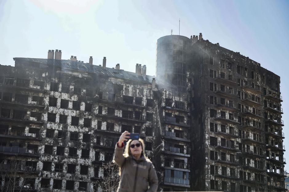 Una mujer se toma una foto junto al edificio de Campanar, Valencia, una vez apagadas las llamas