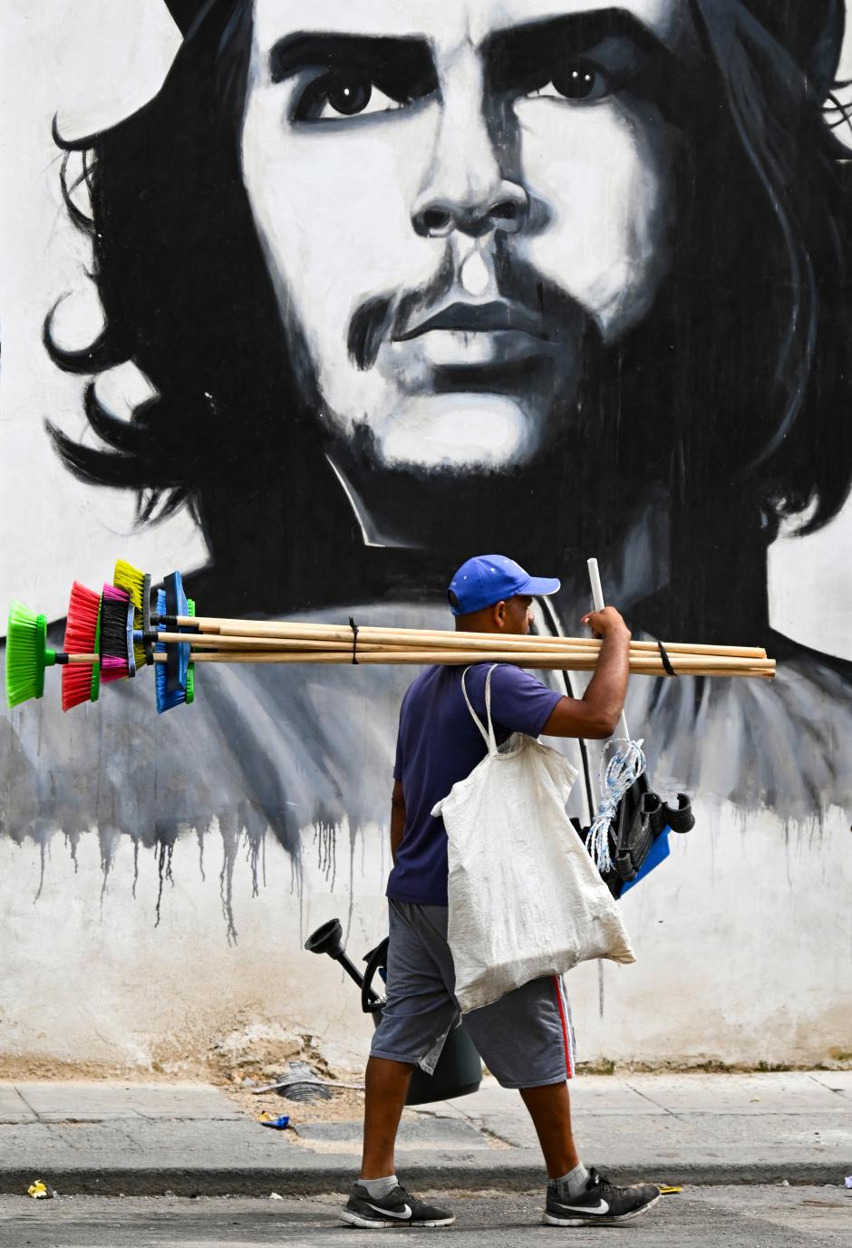 Un vendedor ambulante en La Habana pasa por delante de un mural con el rostro del Che Guevara