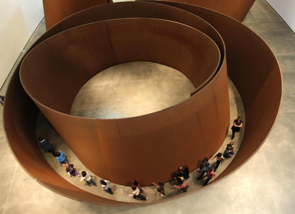 Varias personas recorren la pieza escultórica del estadounidense Richard Serra titulada "La materia del tiempo"