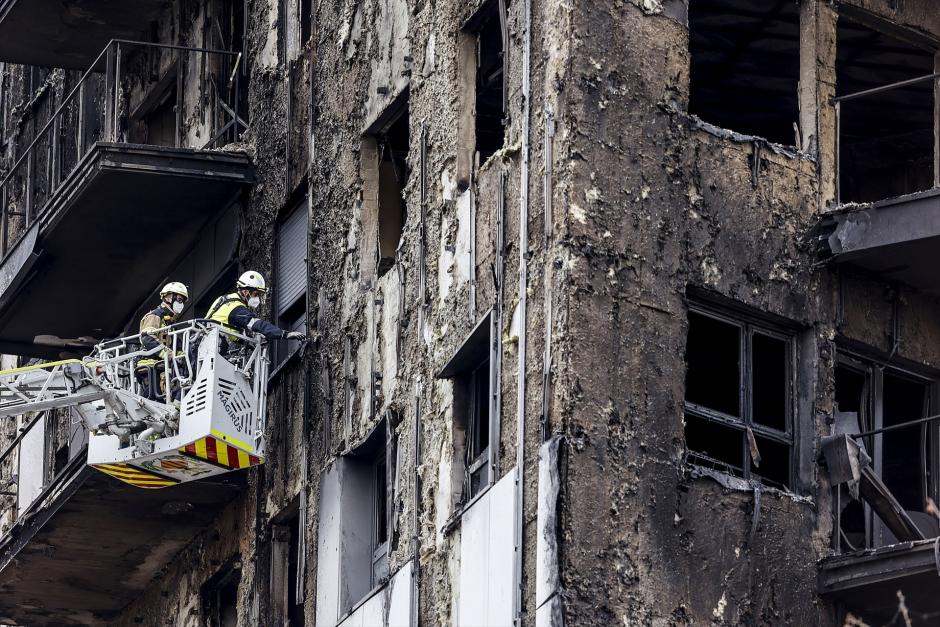 Bomberos en una grúa sanean la fachada quemada