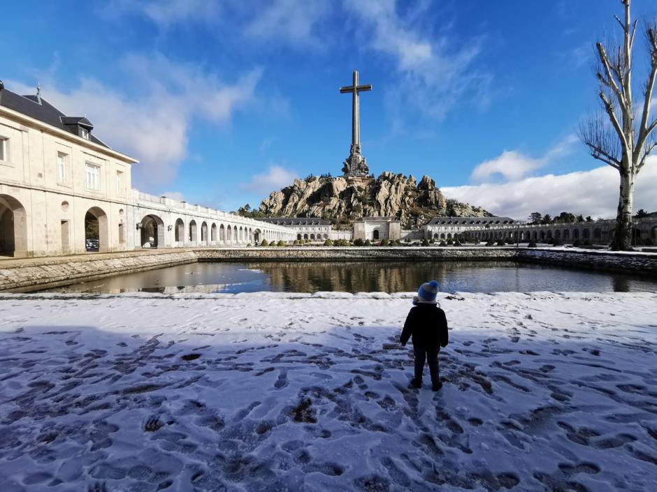 Un niño contempla la cruz del Valle en medio de la nieve