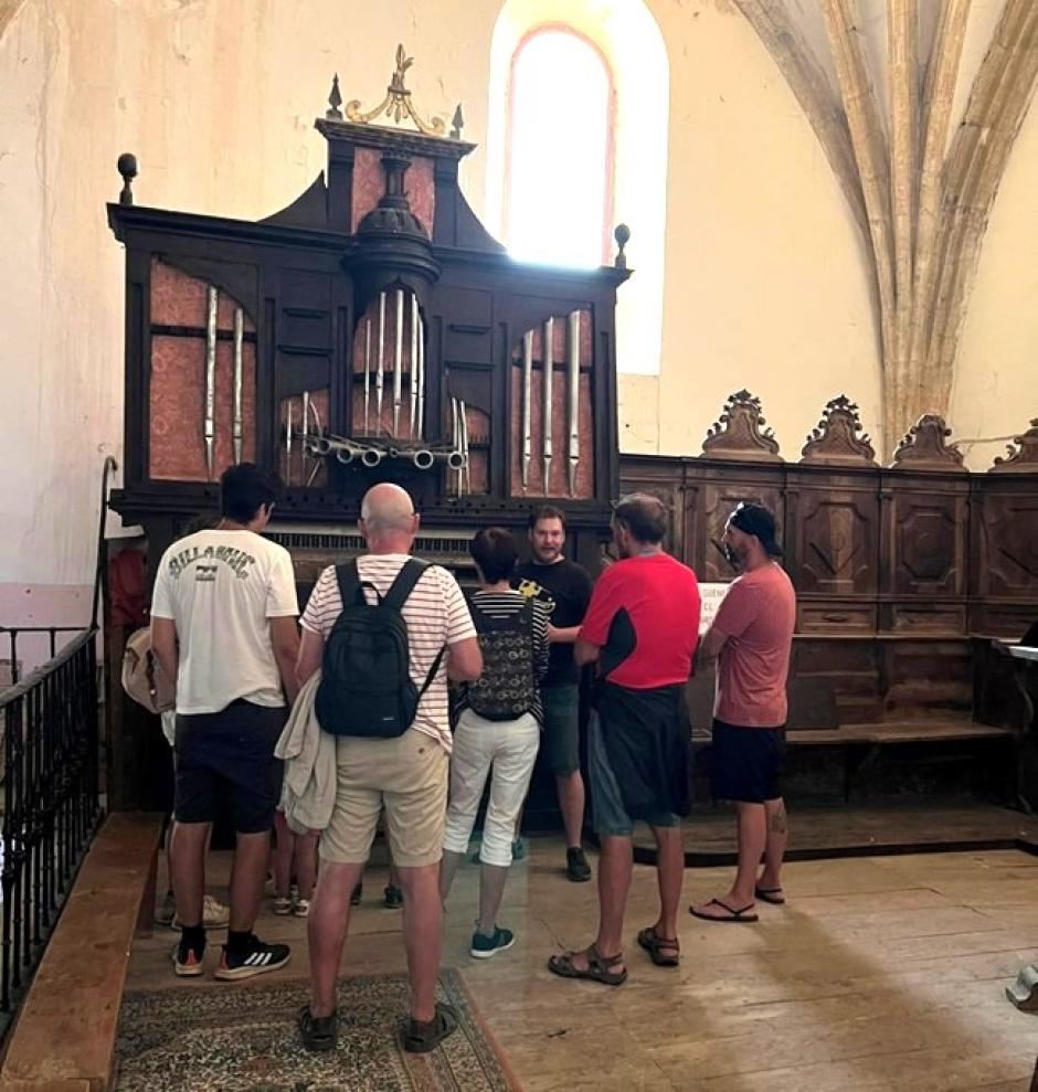 Un voluntario explica a unos turistas las peculiaridades del órgano barroco de Busto