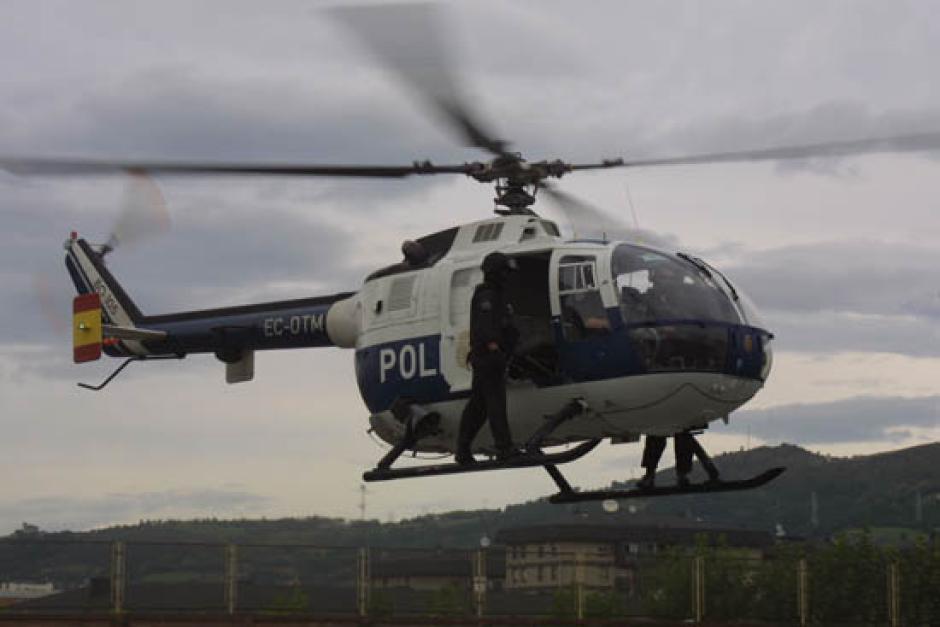 Un helicóptero de la Policía Nacional en vuelo con dos agentes en el exterior