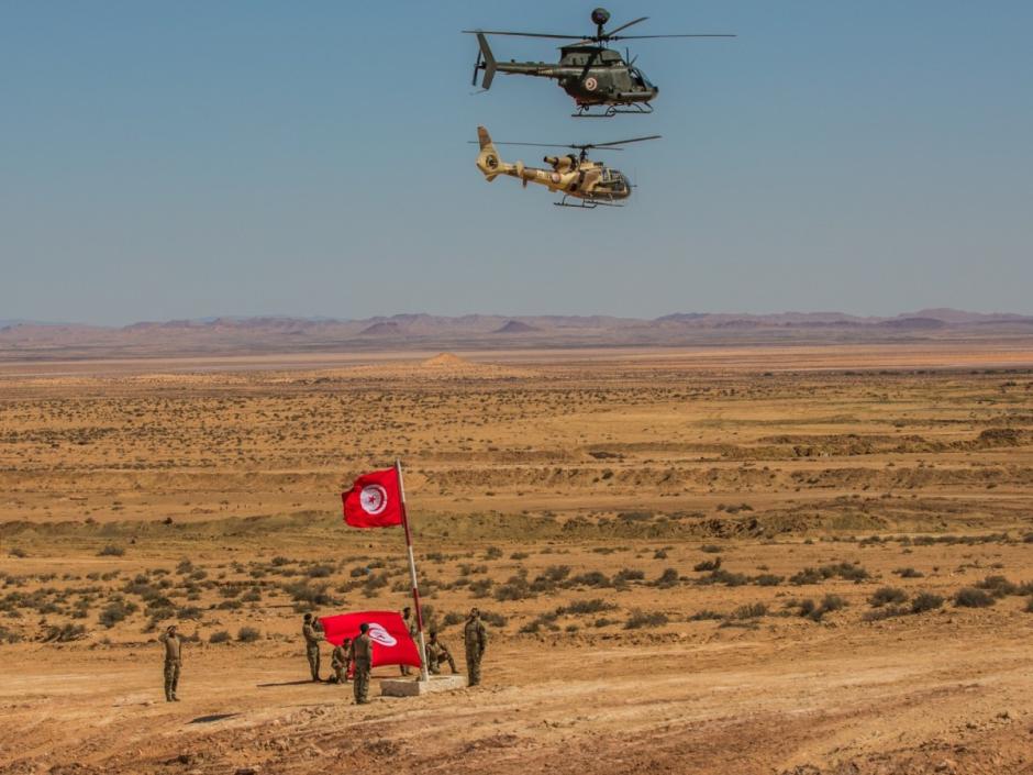 Helicópteros tunecinos Bell OH-58 Kiowa Warrior y Gazelle sobrevuelan las Fuerzas Especiales de Túnez mientras izan la bandera tunecina