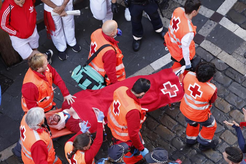 Miembros de los servicios sanitarios evacúan a un herido en la calle Estafeta durante el primer encierro de los Sanfermines