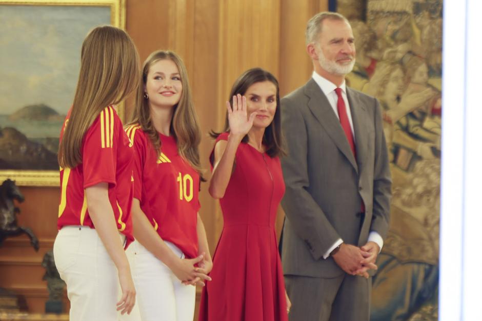 La Reina saluda mientras espera junto al Rey a sus hijas la llegada de los jugadores