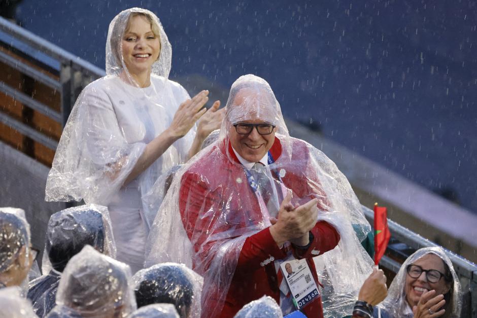 El Príncipe Alberto II de Mónaco (R) y la Princesa Charlene de Mónaco, vestidos con impermeables