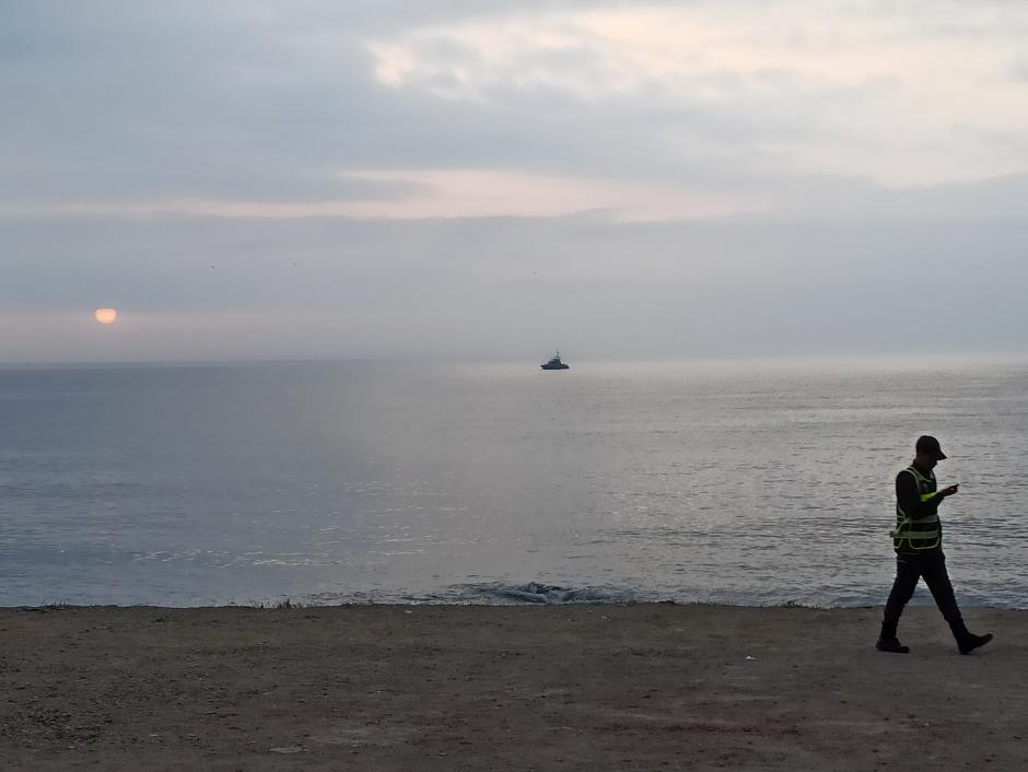 Un 'mejani' camina por la costa mientras una patrullera vigila desde alta mar