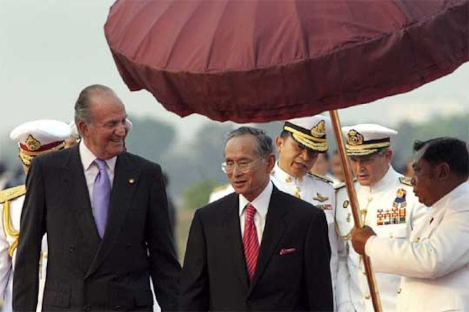 Don Juan Carlos conversa con el rey de Tailandia, Bhumibol Adulyadej, a su llegada a Bangkok, en 2006