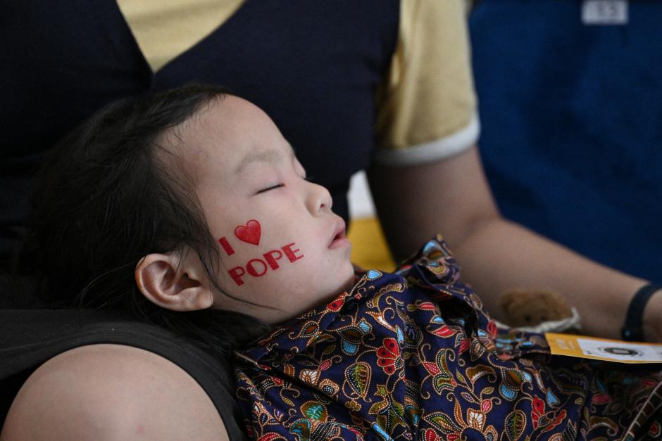 A child falls asleep as Catholic faithful wait to attend the holy mass led by Pope Francis at the National Stadium in Singapore on September 12, 2024. (Photo by Tiziana FABI / AFP)