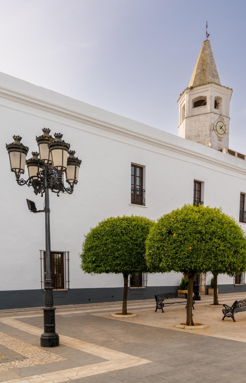 Olivenza, Spain - 27 March, 2022: orange trees and whitewashed buildings under a blue sky on the Plaza de la Constitucion Square