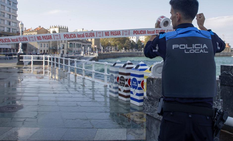 Un agente de la Policía Local de Gijón cierra un tramo del paseo marítimo de San Lorenzo