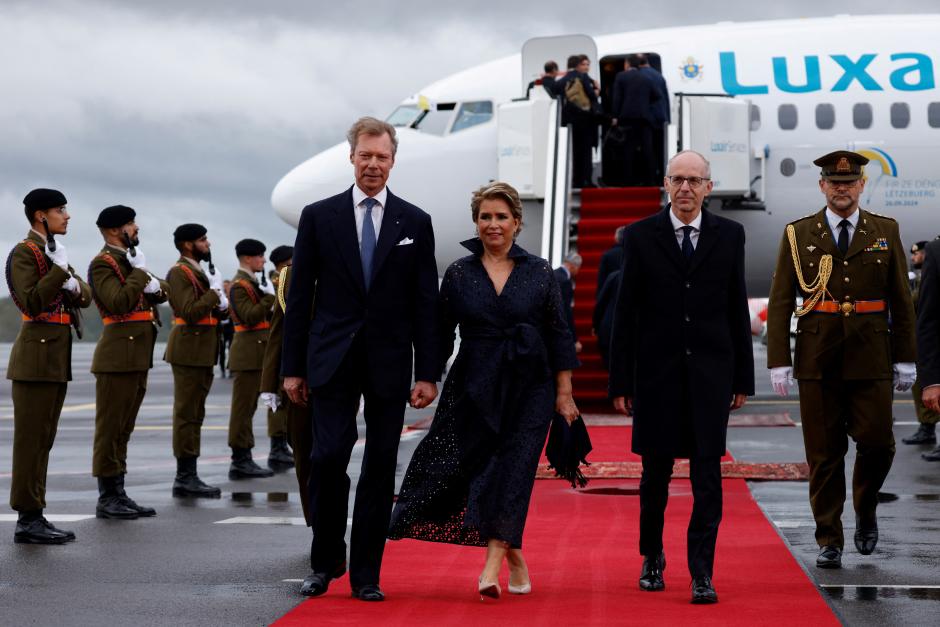 Grand Duke Henri of Luxembourg (L), Grand Duchess Maria Teresa of Luxembourg (C) and Luxembourg's Prime Minister Luc Frieden (R) walk after a farewell ceremony for the Pope's departure following his visit to Luxembourg, at Luxembourg Findel Airport on September 26, 2024. The pope is on a four-day apostolic journey to Luxembourg and Belgium. (Photo by SIMON WOHLFAHRT / AFP)