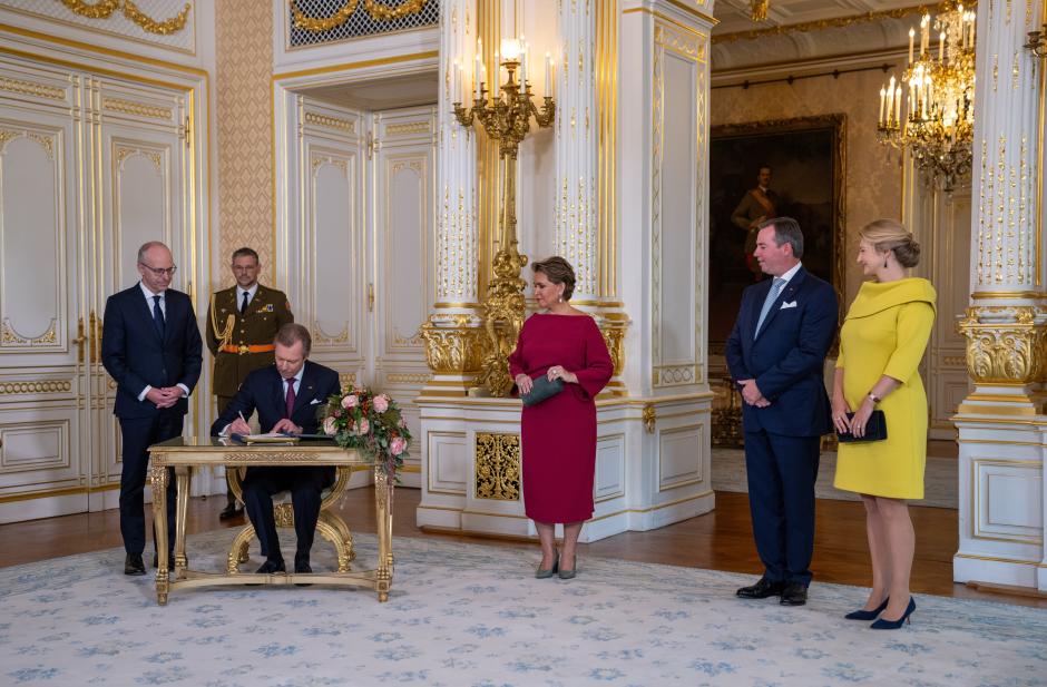 08 October 2024, Luxembourg, Luxemburg: Henri (3rd from left), Grand Duke of Luxembourg, signs the document appointing his son Guillaume (2nd from right) as "Lieutenant-Représentant" (Honorary Lieutenant) in the presence of Luc Frieden (l), Prime Minister of Luxembourg, Grand Duchess Maria Teresa (M) and Princess Stephanie (r) in the ducal palace. Grand Duke Henri has appointed his son Prince Guillaume as Lieutenant-Représentant, thus initiating the handover of office. The 42-year-old now takes over certain tasks from his father, while the latter remains Head of State. Photo: Harald Tittel/dpa *** Local Caption *** .