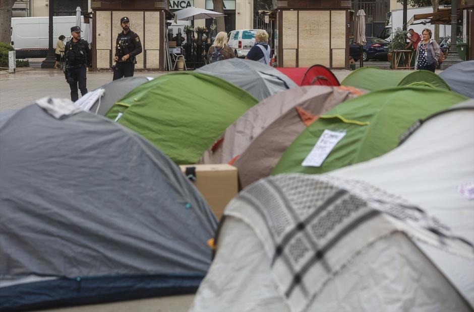 Dos agentes de Policía Nacional junto a las tiendas de campaña durante la acampada de vivienda en la Plaza del Ayuntamiento de Valencia