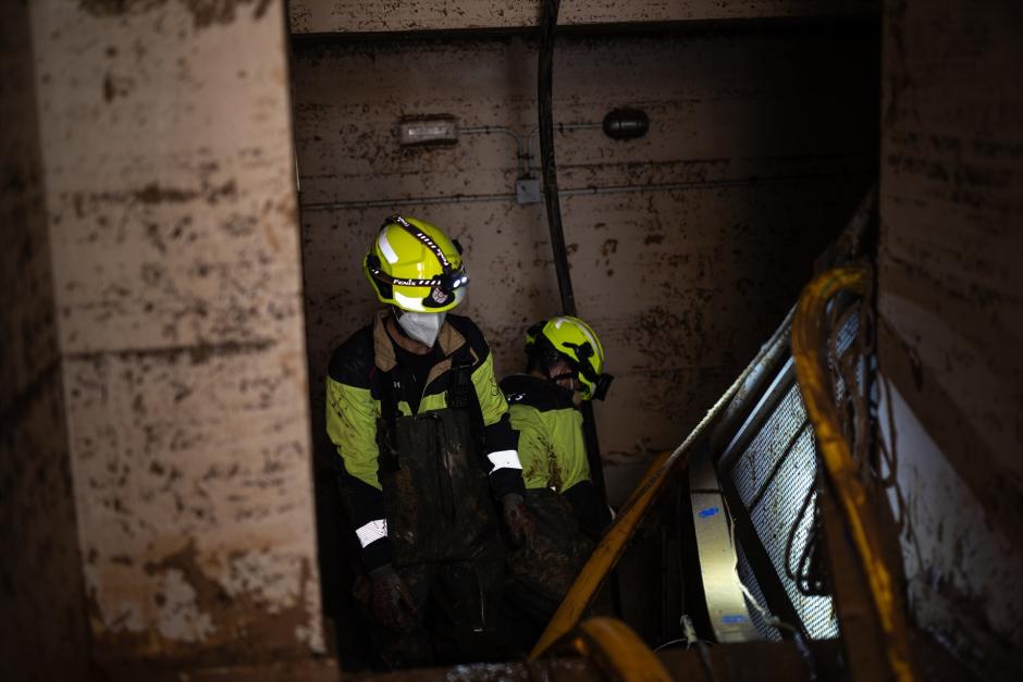 Varios bomberos revisan en Benetúser (Valencia) un garaje inundado por la DANA