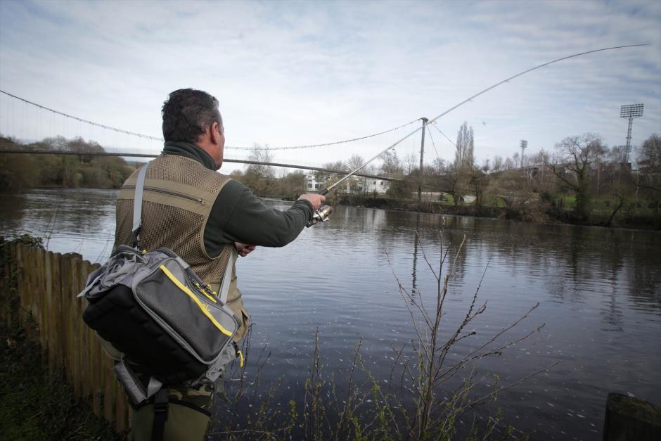 Un pescador, lanza la caña en el río, durante el primer día de temporada de pesca