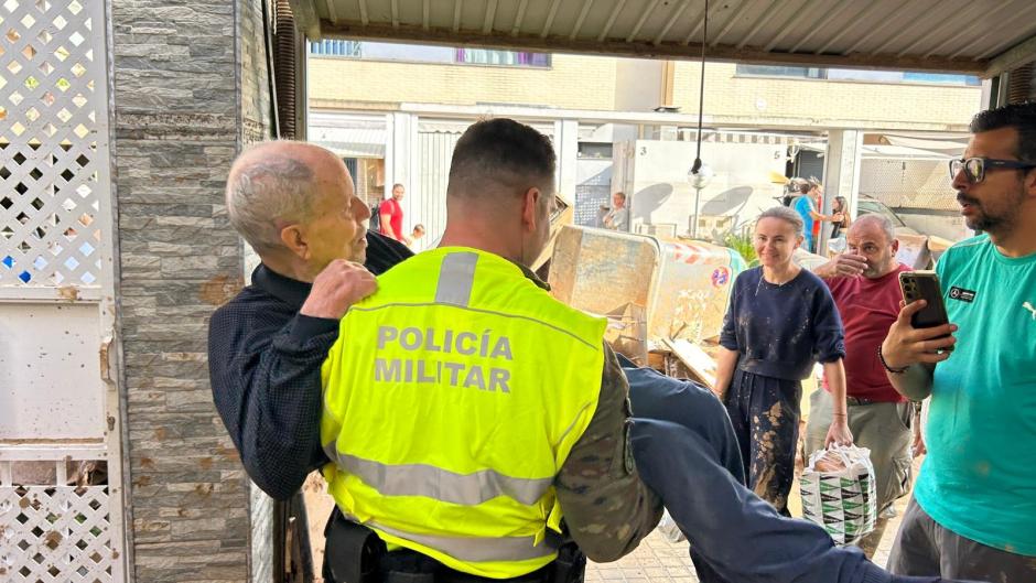 Un miembro de la Policía Militar socorre a un hombre afectado por la DANA