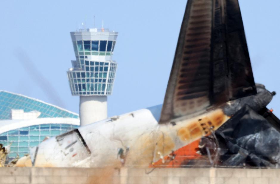 Los restos del avión de Jeju Air y la torre de control del aeropuerto de Muan al fondo