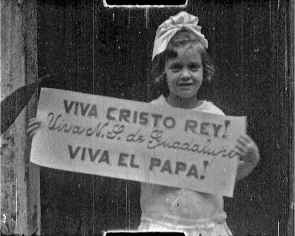 Una niña con un cartel de ¡Viva Cristo Rey!