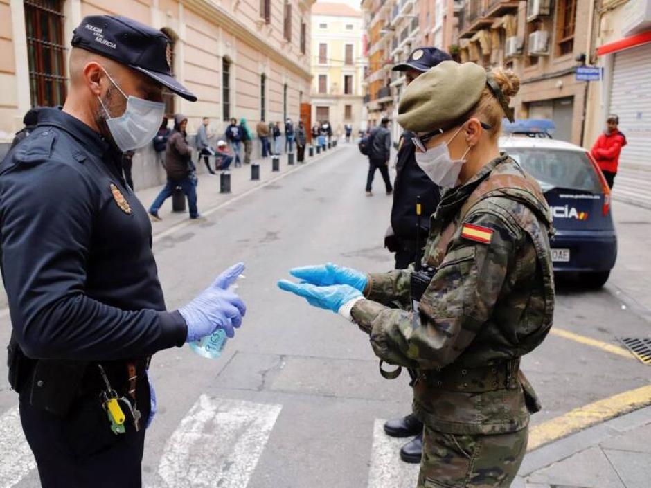 Un Policía Local de Murcia, ofrece gel desinfectante a una militar del Ejército de Tierra