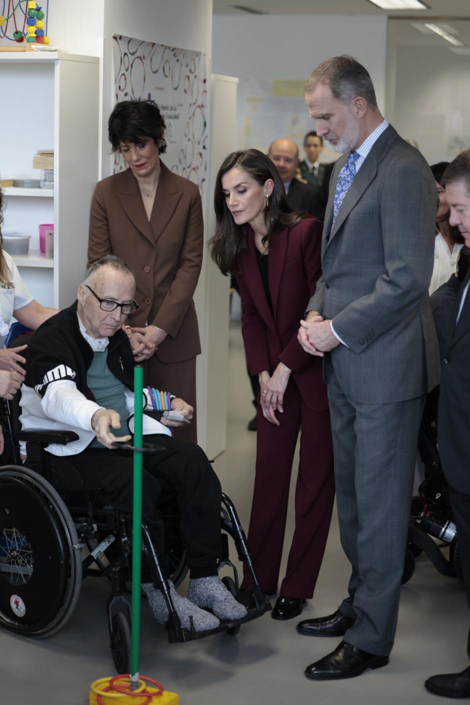 Don Felipe y Doña Letizia conversan con un paciente que realiza unos ejercicios