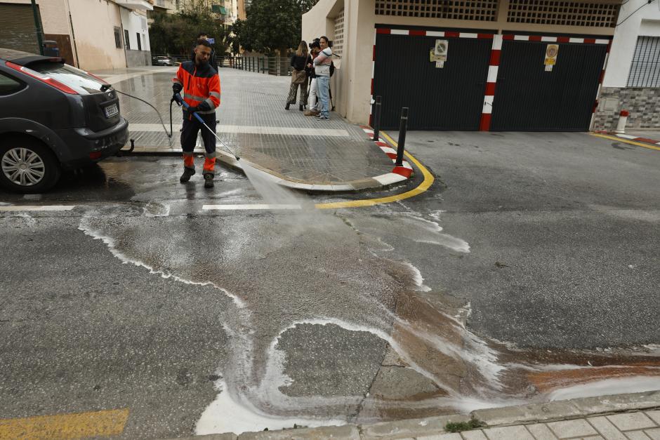 Un trabajador del Ayuntamiento de Málaga baldea la zona donde un hombre y una mujer han fallecido tras precipitarse este martes al vacío desde un edificio ubicado en la calle María Teresa de Calcuta