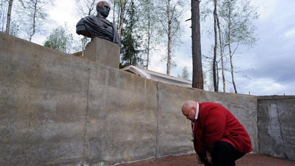 Un hombre se arrodilla ante la estatua de Putin a la romana