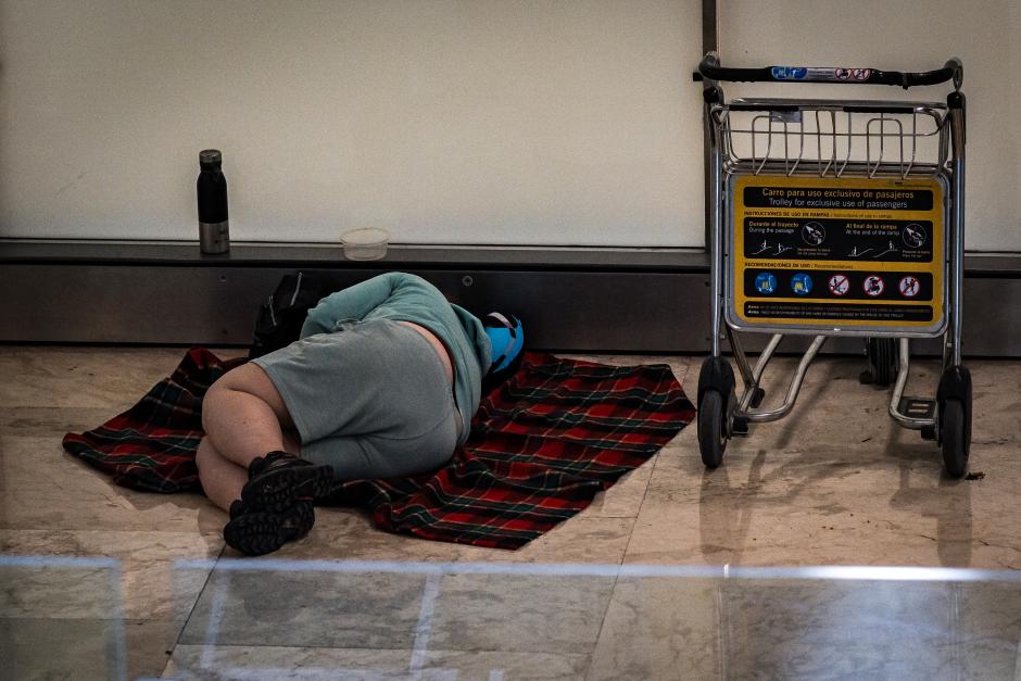 Una persona duerme en la T4 del Aeropuerto Adolfo Suárez-Madrid Barajas
