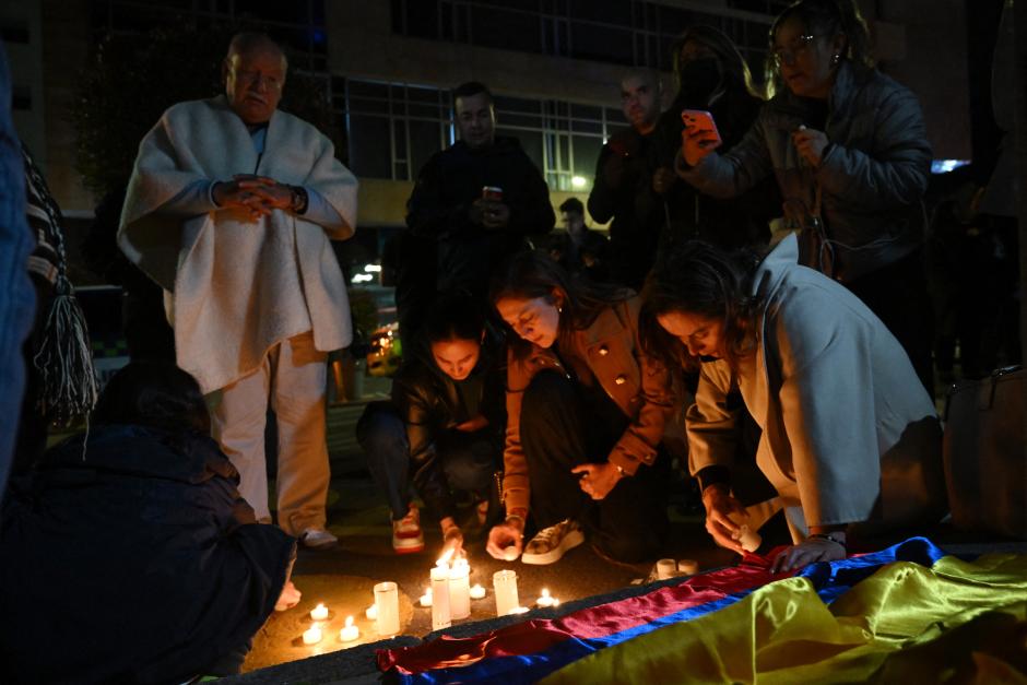 Personas encienden velas y rezan frente a la Clínica Fundación Santa Fe, donde el senador Miguel Uribe Turbay