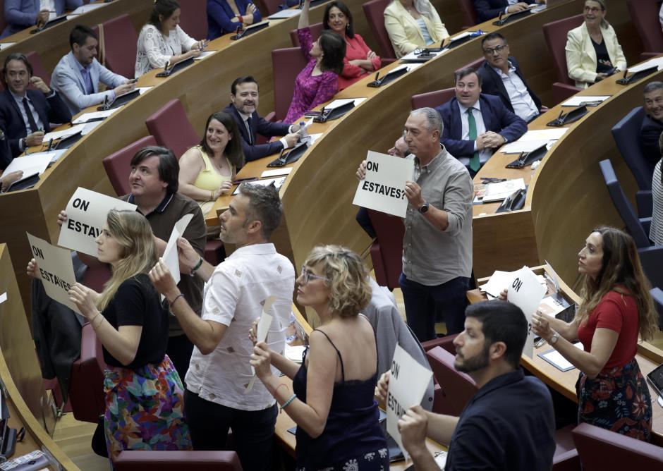 Los diputados de Compromís, mostrando los carteles de pie en sus escaños