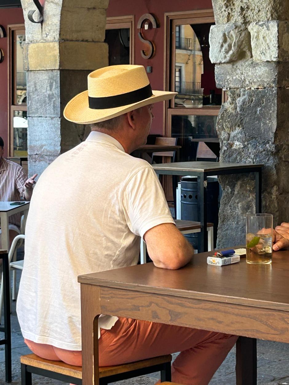 Una persona tomando algo en una terraza con un paquete de tabaco encima de la mesa
