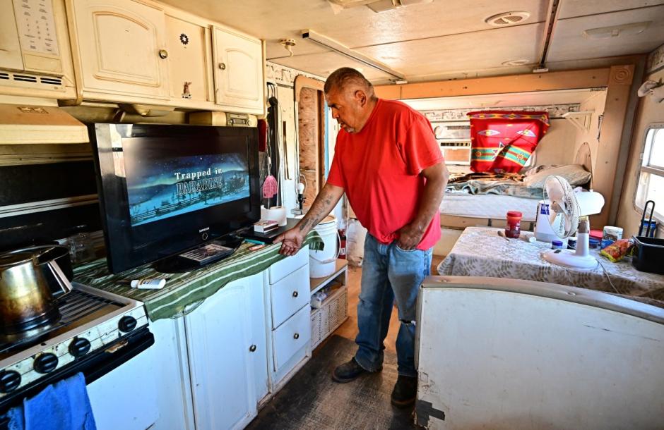 Navajo Nation resident Elbert Yazzie, 54, turns on his DVD player inside his tiny home after recently getting connected to the power grid for electricity on July 8, 2025 in Tuba City, Arizona. Initiatives like "Light Up Navajo," a project launched by the semi-autonomous government of the reservation in 2019, are connecting homes to the power grid with help from volunteer utility crews and federal funding but challenges remain due to the dispersed nature of the communities and vastness of the reservation. (Photo by Frederic J. BROWN / AFP)
