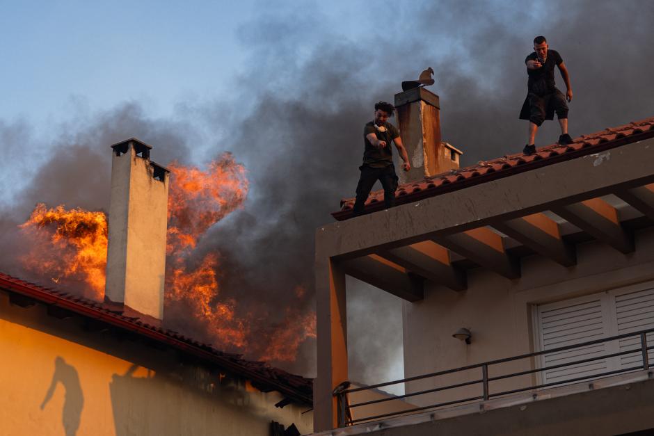 Los residentes locales intentan extinguir el fuego de una casa en llamas durante un incendio forestal en Kryoneri