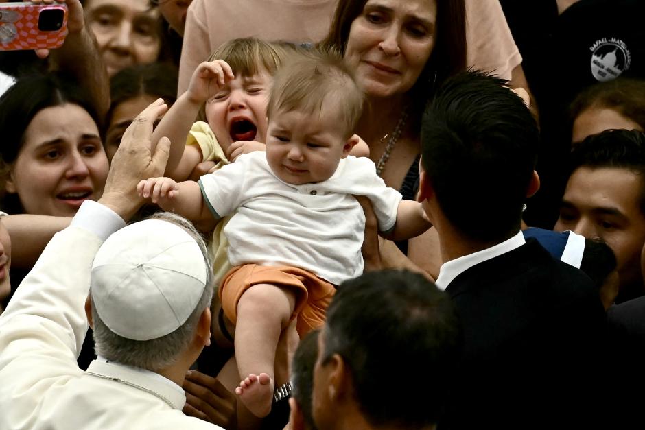 Pope Leo XIV holds a toddler during the general audience in Paul VI Hall at the Vatican on August 27, 2025. (Photo by Filippo MONTEFORTE / AFP)