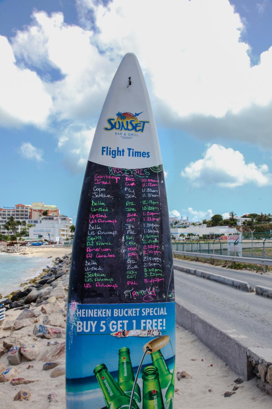 Pizarra del Sunset Bar de Maho Beach con los horarios de los vuelos