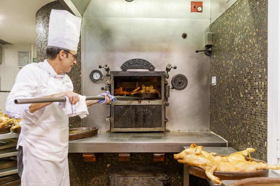 Un cocinero mete en el horno una bandeja de cochinillos, en Segovia