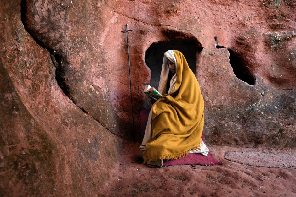 Fiel etíope leyendo un libro sagrado en una iglesia excavada en la roca en Lalibela