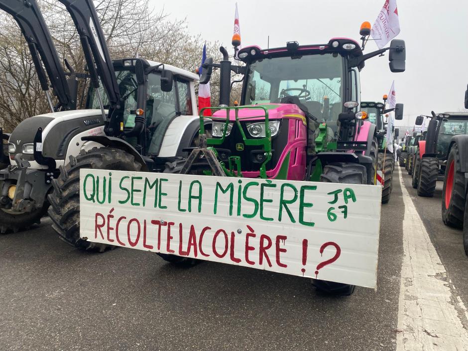 Pancarta 'Quien siembra la miseria recolecta la colera' en un tractor en Estrasburgo