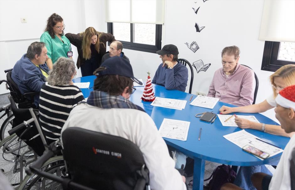 Varias personas mayores leen y escriben en una mesa