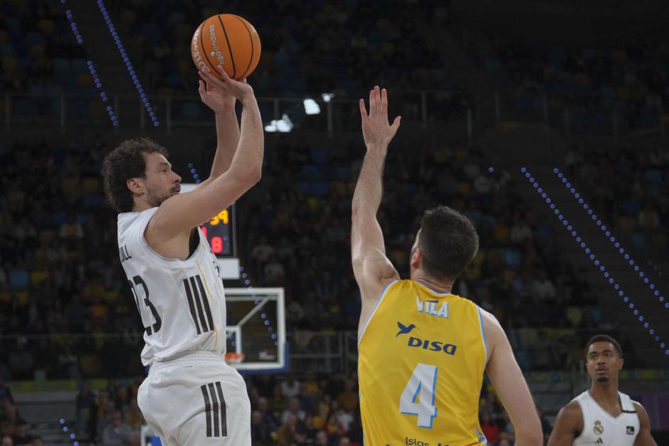 El base del Real Madrid Sergio Llull (i) lanza ante el ala pívot del Gran Canaria Eric Vila
