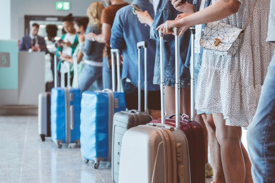 Fila de pasajeros con su equipaje en el aeropuerto