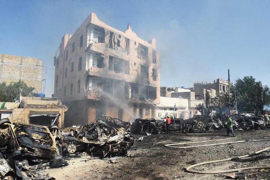 Voluntarios junto a los daños causados por la explosión del tren en Pakistán. Varios coches y edificios se vieron afectados