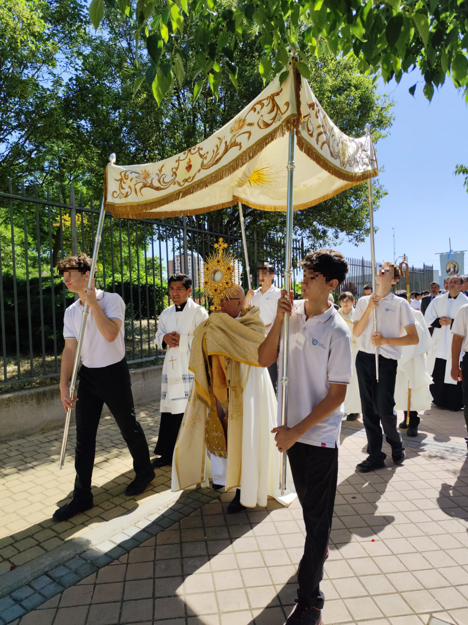 Mons. Avendaño procesiona con la custodia, mientras alumnos del Colegio Juan Pablo II de Parla portan el palio