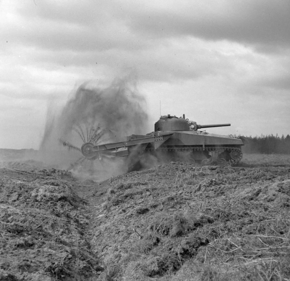 Tanque antiminas M4 Sherman con torreta trasera en acción. El mayal frontal detona las minas