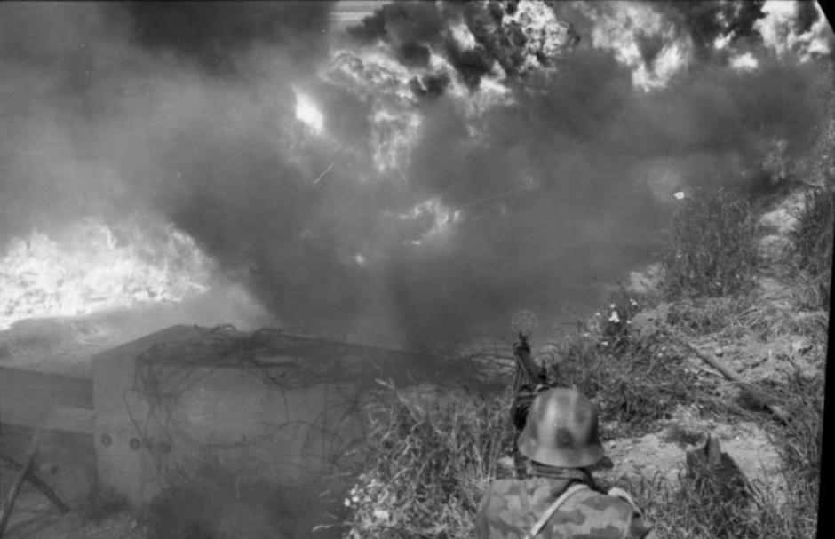 Un ametrallador alemán, cuyo campo de visión está limitado por nubes de humo, custodia un bloqueo de carretera durante un ejercicio de entrenamiento